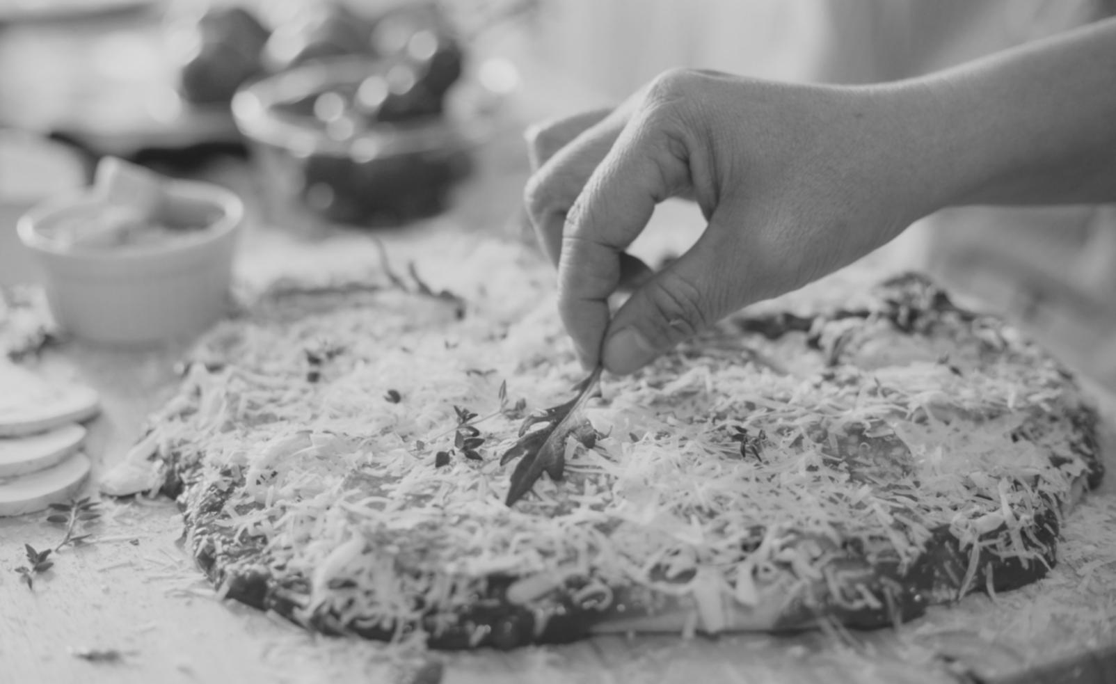 Freshly stretched pizza dough with flour dust on a wooden work surface, showing the handcrafted preparation process in our masterclass kitchen